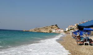 een strand met stoelen en parasols en de oceaan bij Dimitris studios in Kokkari