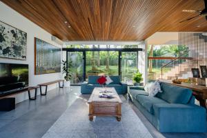 a living room with blue couches and a wooden ceiling at Maxwell Villa Bali in Tabanan