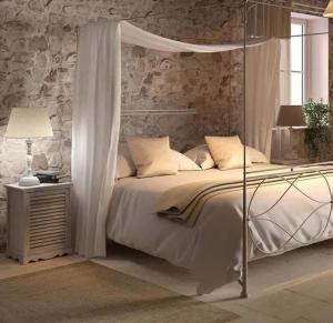 a bedroom with a white bed with a canopy at Cottage in pietra indipendente con parco privato Polvere di Stelle in Monterotondo