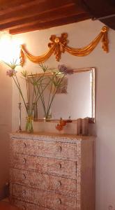 ein Spiegel auf einer Kommode mit Blumen drauf in der Unterkunft Cottage in pietra indipendente con parco privato Polvere di Stelle in Monterotondo