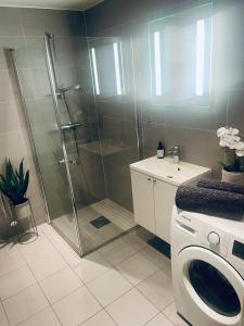 a bathroom with a shower and a washing machine at Sunny, patio & roof terrace Fornebu in Fornebu