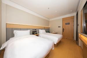 two beds in a hotel room with white sheets at JI Hotel Beijing South Railway Station Muxiyuan in Beijing