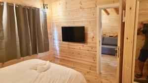 a bedroom with a tv on a wooden wall at בקתות רם-מתחם בקתות מהמם עם בריכה פרטית ונוף מושלם in Sede Terumot