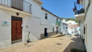 an alley with white buildings and a wooden door at Casa del Valle Encantado in Galaroza