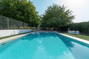 a large blue swimming pool with a fence and trees at Cortijo Villa Ilusion in Arroturas