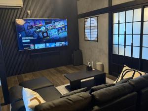 a living room with a couch and a flat screen tv at 一棟貸し宿 ｍａｉｃｃａ in Numazu