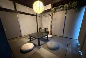 a room with a table and two white ottomans at 一棟貸し宿 ｍａｉｃｃａ in Numazu