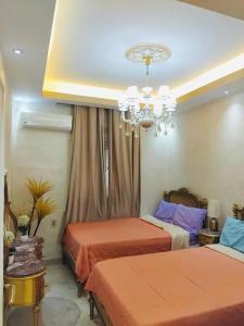 a bedroom with two beds and a chandelier at LuXury Apartment Agouza-Mohandesin in Cairo