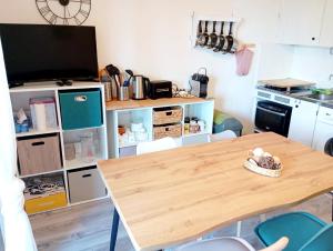 cocina con mesa de madera y TV en app 2ch au calme Barcelonnette vue montagne, en Barcelonnette
