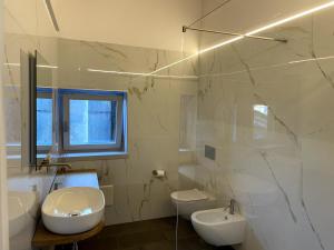 a white bathroom with a sink and a toilet at Attico vista Lago in Centro in Luino +11 photos