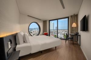a bedroom with a large white bed and a large window at Caro Premium Danang Hotel in Danang