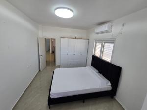 a bedroom with a bed with white sheets and a window at GK Apartments Urban Comfort Balfour in Bat Yam