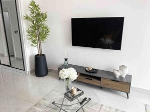 a living room with a tv and a table with flowers at Legit Luxury Apartment at Accra KASS Towers in Accra