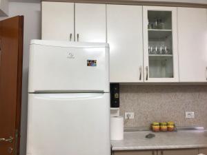 a white refrigerator in a kitchen with white cabinets at Apartament Astir in Tirana