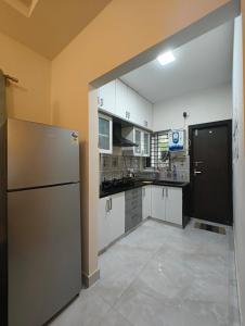 a kitchen with white cabinets and a stainless steel refrigerator at M's Cozy Unwind - Hazel in Bengaluru +12 photos
