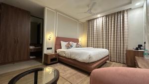 a bedroom with a bed and a table and a chair at Sanguine Varanasi in Varanasi