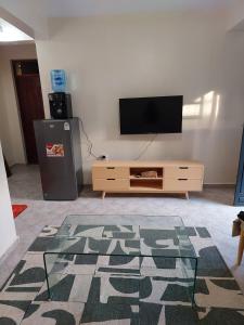 Una sala de estar con un televisor de pantalla plana y una mesa. en 1 bedroom Homabay, en Homa Bay