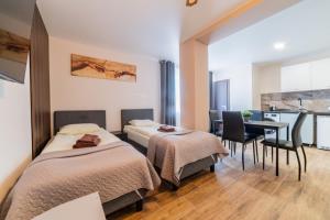 two beds in a room with a table and a kitchen at Svečių namai Imperija in Šiauliai
