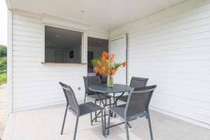 a table and chairs on a porch with a vase of flowers at La fleur des îles - Maison Climatisé pour 4 in Morne-à-lʼEau