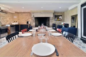 a long table with white plates and chairs in a room at Castel Dolais - Magnifique Manoir pour 8p in Saint-Onen-la-Chapelle
