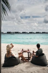 a man and a woman sitting on the beach at Park Hyatt Maldives Hadahaa in Gaafu Alifu Atoll
