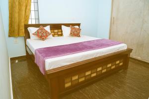 a bedroom with a large bed with purple sheets and pillows at Madhava Home Stay in Tirupati