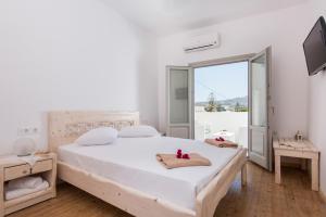 a white bedroom with a large bed and a window at Villa Aegeon Grande in Megalochori +40 photos