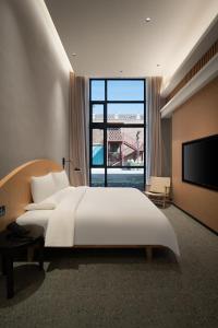 Koktokay可可托海的梦·非遗度假酒店的卧室里有一张白色的大床和一扇大窗户 更多73张照片