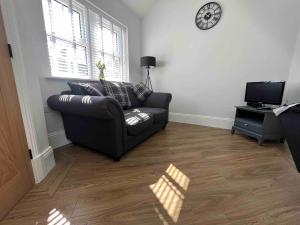 a living room with a couch and a clock on the wall at 4 Mulberry Green , Waterfoot , Rossendale, Lancs in Newchurch
