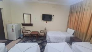 a room with two beds and a tv on the wall at فندق جوهرة الشروق in Az Zahrāʼ +6 photos