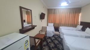 a hotel room with three beds and a mirror at فندق جوهرة الشروق in Az Zahrāʼ