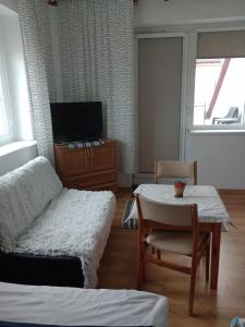 a living room with a table and a chair and a tv at Pokoje Klaudia in Darłowo