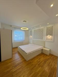 a bedroom with a bed in a room with wooden floors at Riga Lux Apartment Prishtina in Pristina