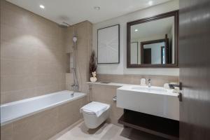 a bathroom with a tub and a toilet and a sink at KeyRock - Dubai Marina Stay with Pool & Gym in Dubai