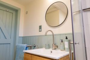 a bathroom with a sink and a mirror on the wall at The Little Stable - Cosy 1 Bed Cottage in Burford in Swinbrook +8 photos