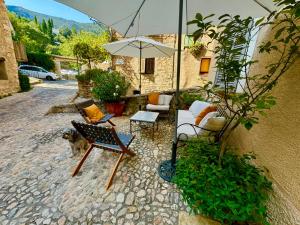 a patio with furniture and an umbrella and a dog at La Vicomtesse de Seillans in Seillans