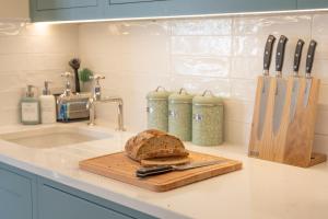 a loaf of bread on a cutting board on a kitchen counter at The Little Stable - Cosy 1 Bed Cottage in Burford in Swinbrook