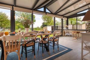 einen Wintergarten mit einem Tisch und Stühlen auf einer Terrasse in der Unterkunft La villa Léa in Saint-Gildas-de-Rhuys