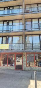 ein hohes Gebäude mit Glasfenstern und roten Türen in der Unterkunft Bakuriani Mgzavrebi Block 9 Apartments in Bakuriani