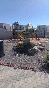 une aire de jeux avec un toboggan jaune dans un parc dans l'établissement Sarona Habitat Urban Escape 1 Bedroom Apartment, à Gaborone