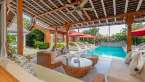 an outdoor living room with a pool and tables and chairs at Villa Taramille by Villa Finder in Kerobokan