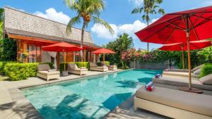 a swimming pool with chairs and umbrellas next to a resort at Villa Taramille by Villa Finder in Kerobokan