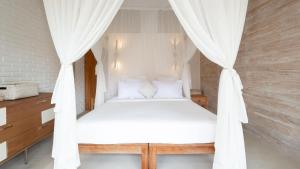 a bedroom with a canopy bed with white curtains at Villa Taramille by Villa Finder in Kerobokan