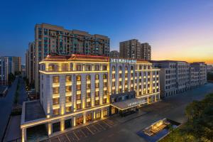 Un edificio iluminado en una ciudad con edificios altos. en Fairfield by Marriott Yining, en Yining