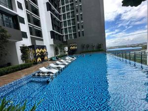 a swimming pool with chaise lounges and chairs on a building at Alinea suites DSM near by shah alam in Shah Alam