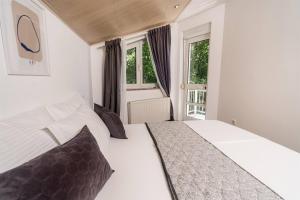a bedroom with a white bed and two windows at ASTAREA - 80m2 penthouse in nature-free parking-terrace-jacuzzi-quiet area in Zagreb