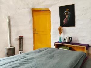 a bedroom with a bed and a yellow door at Spiti Eco Domes in Kaza +8 photos