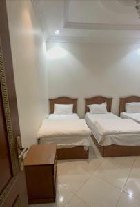 two beds in a room with white walls at شقق دار الخرمة in Al Khurmah