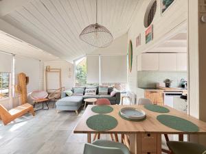 a living room with a table and a kitchen at Olivia Plage, charmante maison lumineuse au calme bien équipée à 100 m plage d Asnelles, 500 m commerces, proche Arromanches et Bayeux, au coeur des plages du débarquement, jardin clos, deux belles terrasses, parking dans propriété in La Celle-sous-Gouzon