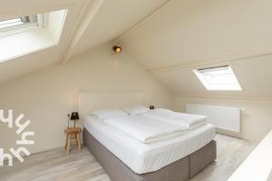 1 dormitorio con 1 cama blanca grande en el ático en Gezellige vakantiewoning met een zonnig terras, en Serooskerke